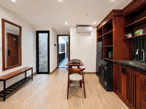 A compact kitchen with a washing machine, a dining area with a bench, and a large mirror. - Sola House Apartment (Da Nang)
