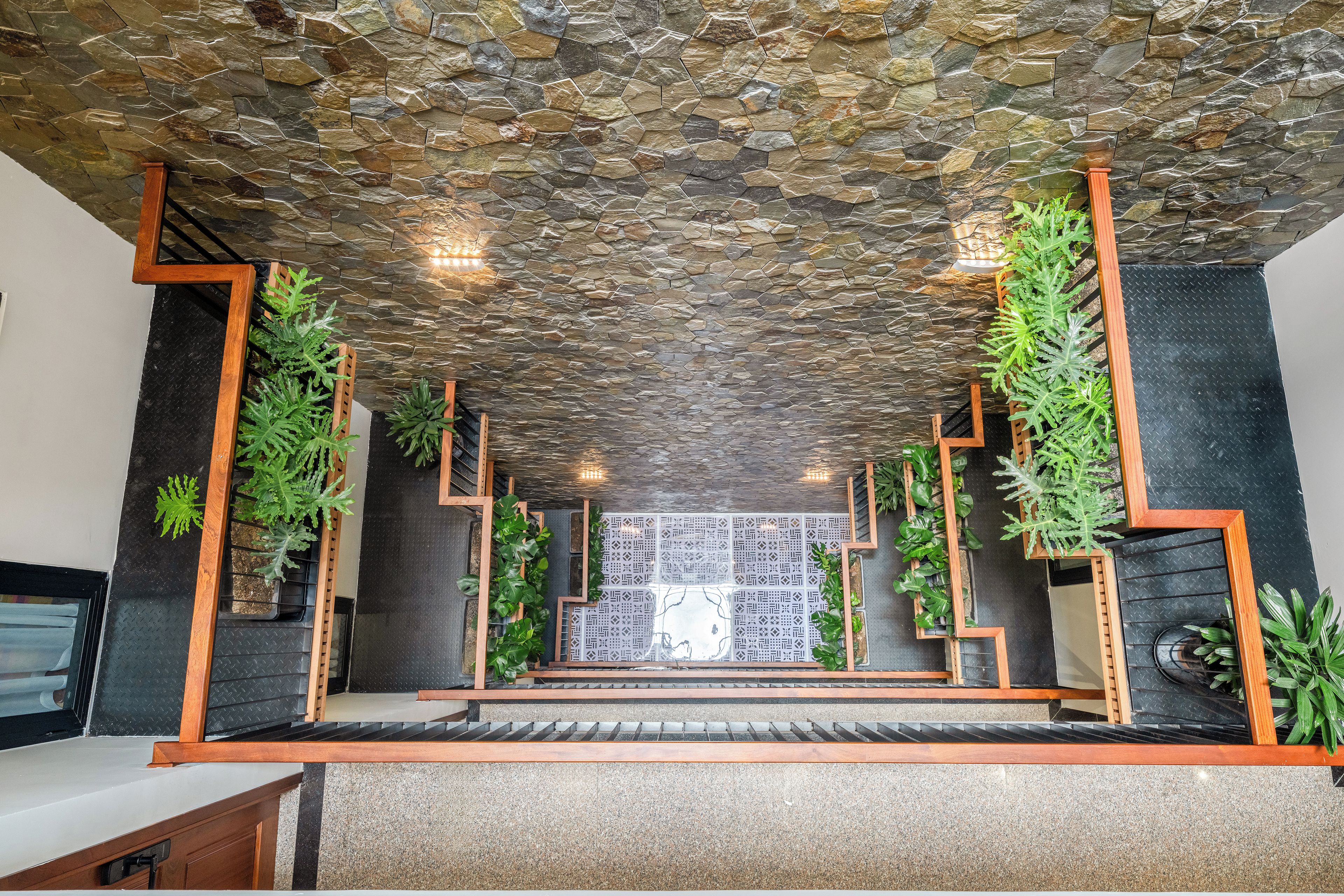 Um interior moderno com teto de pedra, detalhes em madeira e plantas verdes.