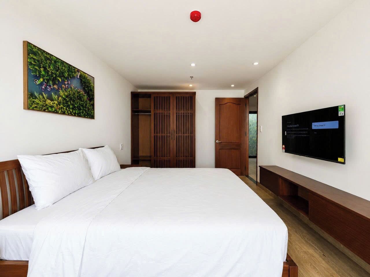 Una habitación de hotel con una cama grande, televisión, armario y un cuadro en la pared.