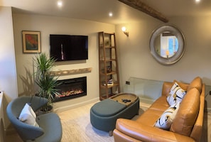 A living room with a fireplace, a television, a sofa, a coffee table, and a bookshelf. - Ullswater retreat near Helvellyn-Bath & EV charger (Glenridding)
