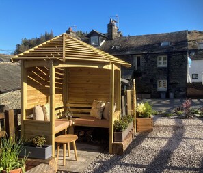 A wooden gazebo with a bench and cushions, surrounded by gravel and potted plants. - Ullswater retreat near Helvellyn-Bath & EV charger (Glenridding)