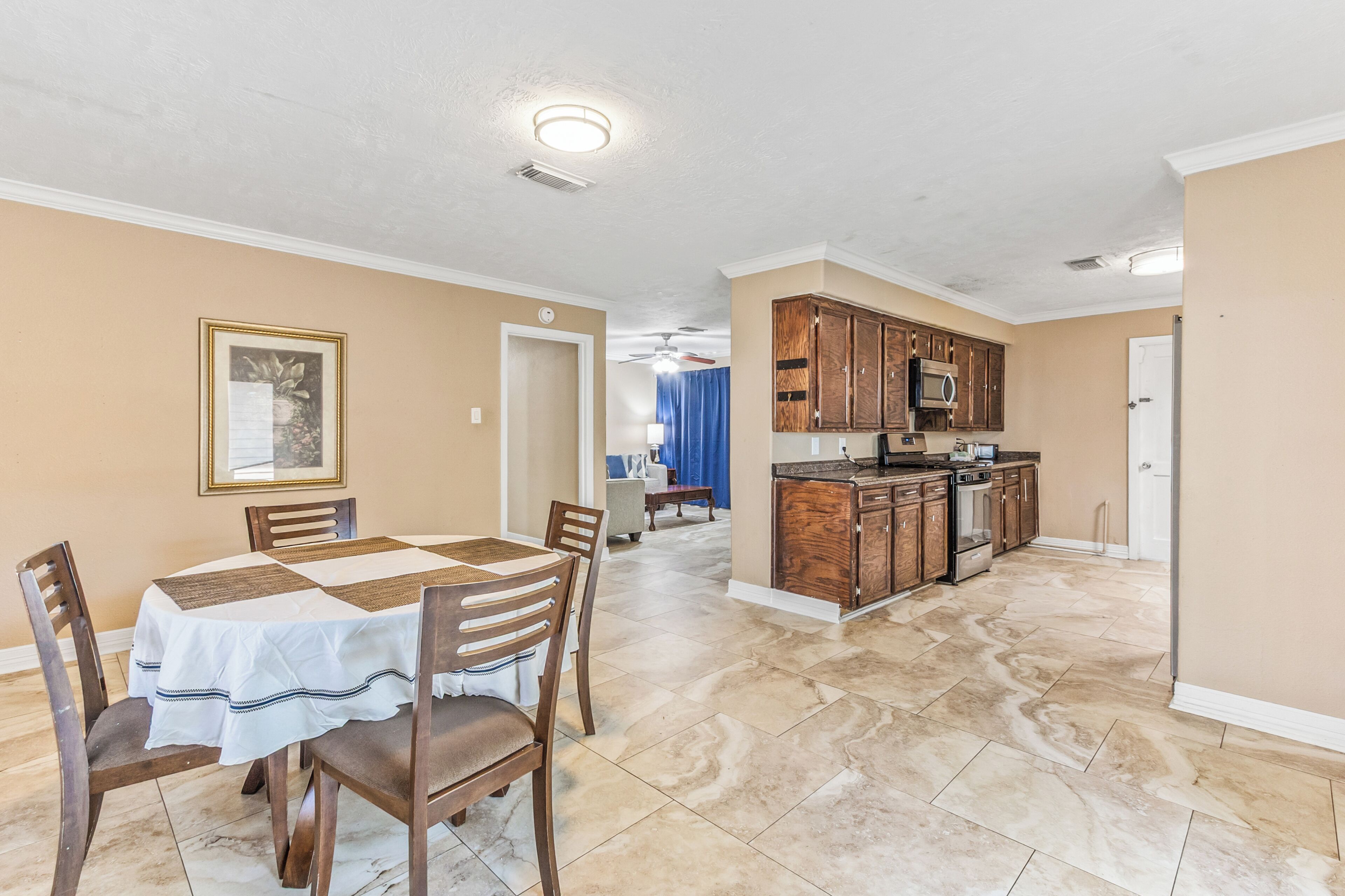 A dining area with a table and chairs, a kitchen with wooden cabinets and appliances, and a hallway with a door.