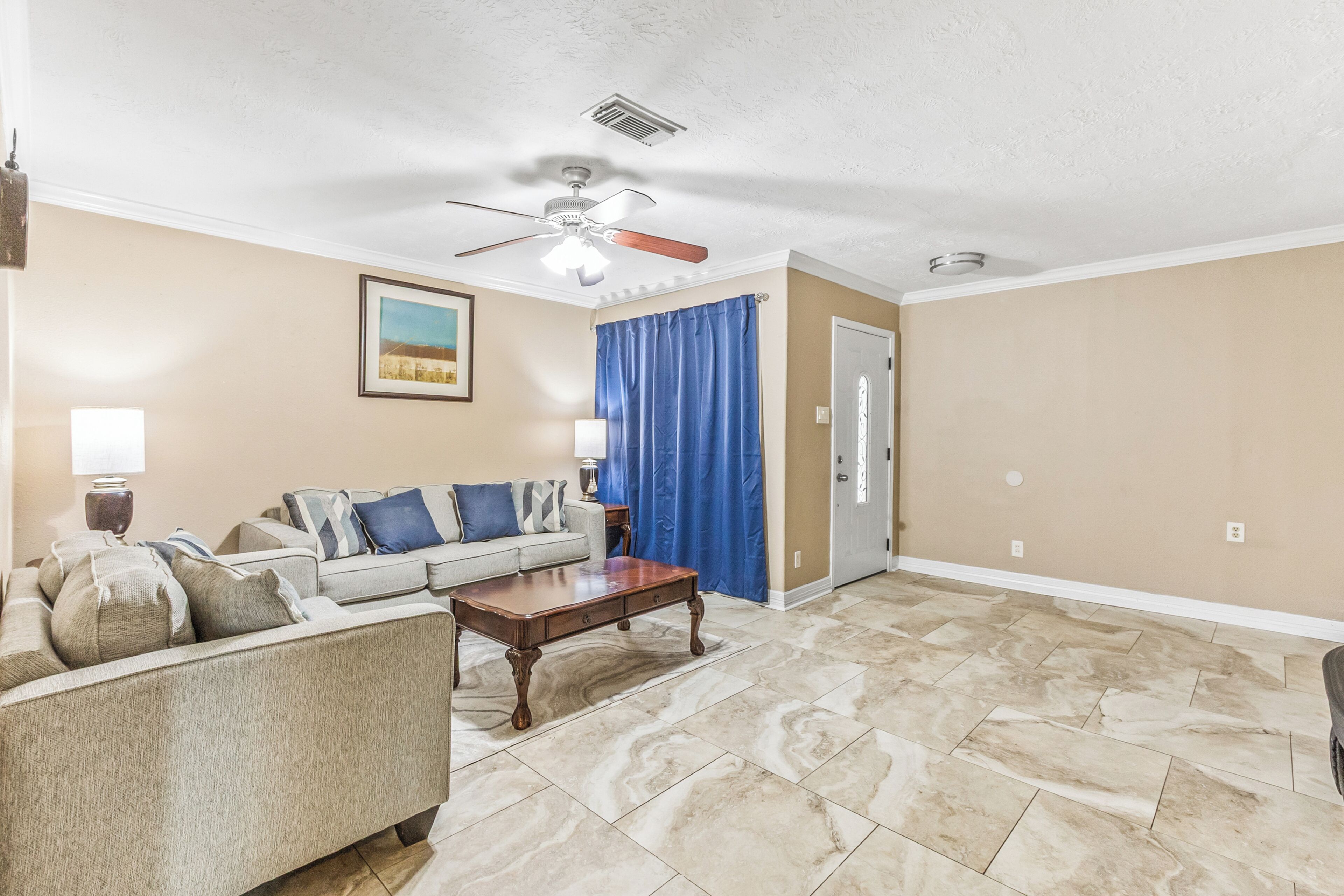 A living room with a ceiling fan, a sofa set, a coffee table, and a door.