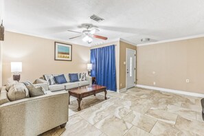 A living room with a ceiling fan, a sofa set, a coffee table, and a door. - Eddy (Pasadena)