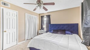 A bedroom with a bed, a ceiling fan, a nightstand, and a window with curtains. - Eddy (Pasadena)