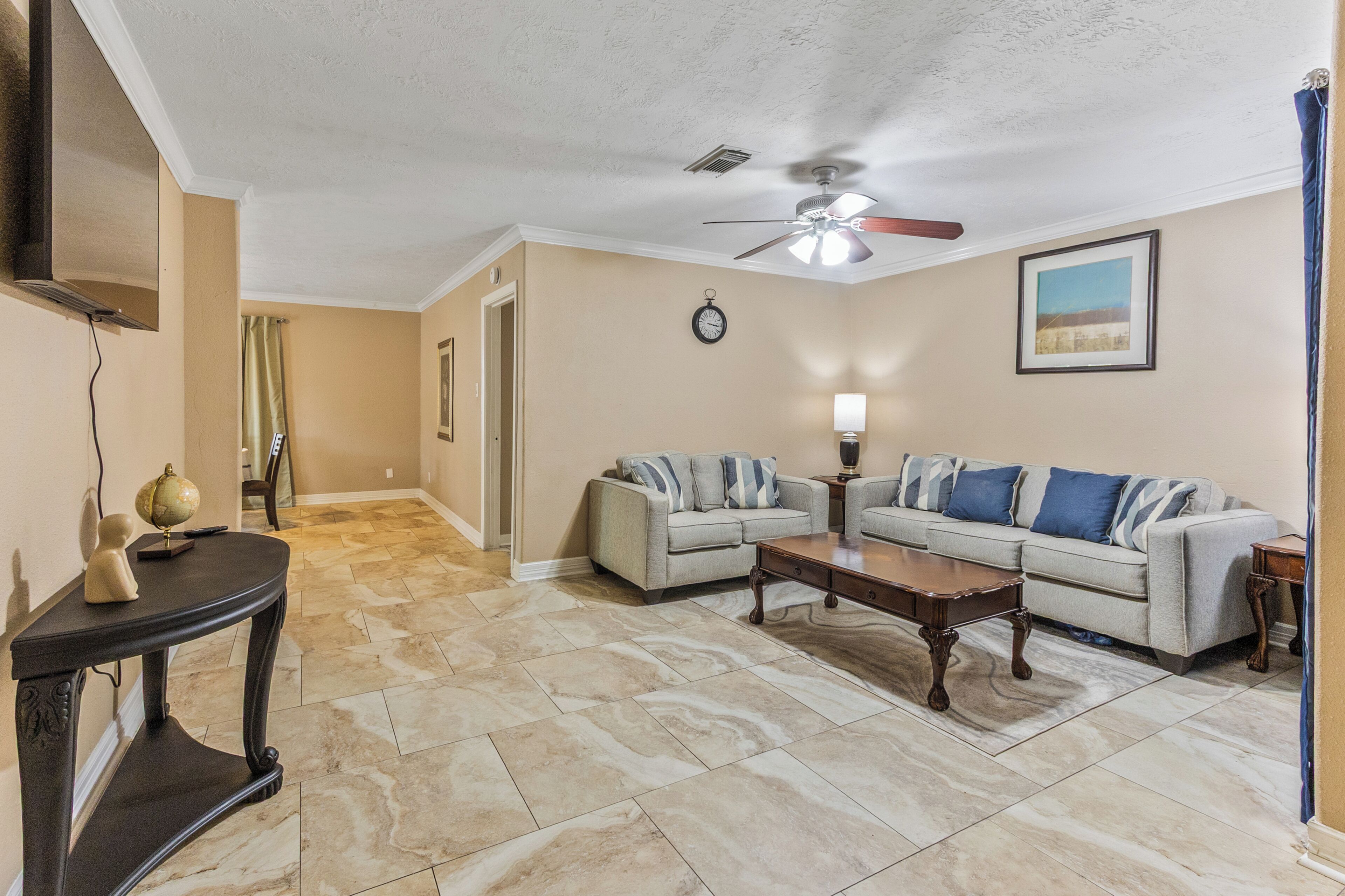 A living room with a ceiling fan, two sofas, a coffee table, and a lamp.