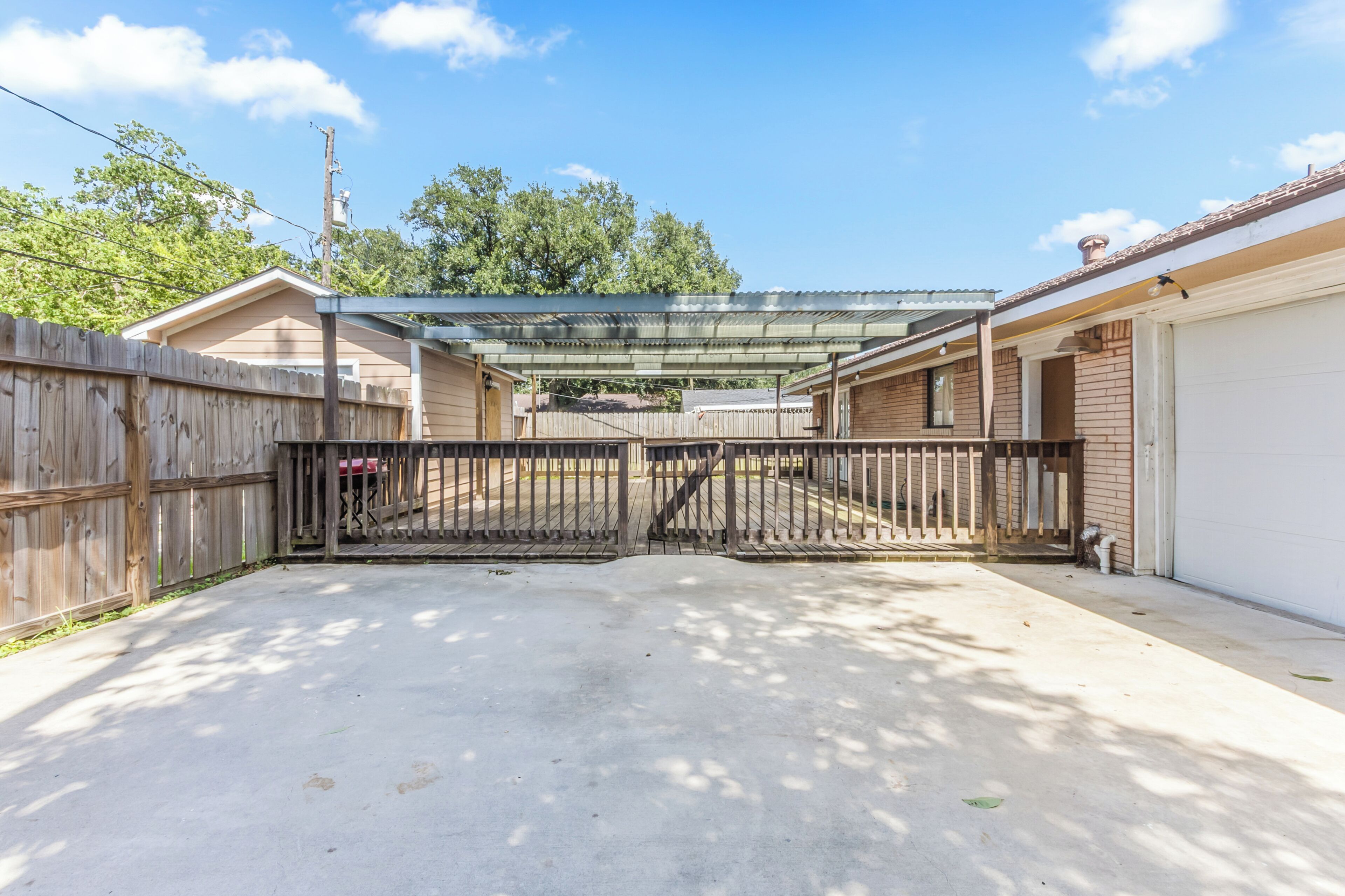 A gated backyard with a covered patio area, a wooden fence, and a garage.