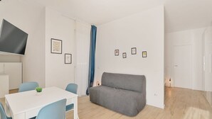 Un soggiorno moderno con un divano grigio, un tavolo bianco e sedie blu.