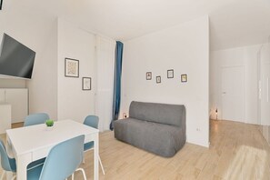 Ein modernes Wohnzimmer mit einem grauen Sofa, einem weißen Tisch und blauen Stühlen.