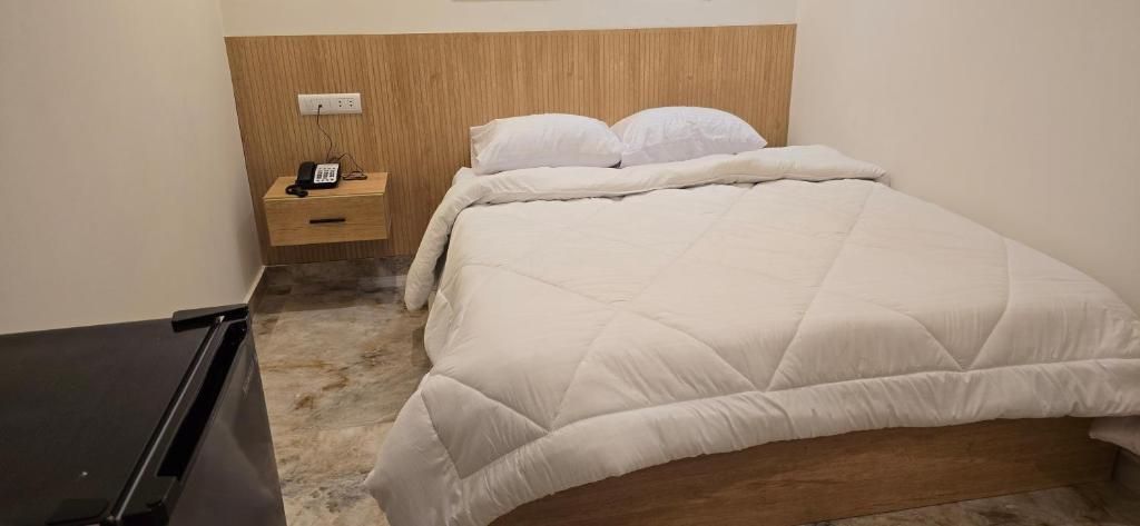 A bedroom with a bed, a bedside table with a phone, and a wall socket.