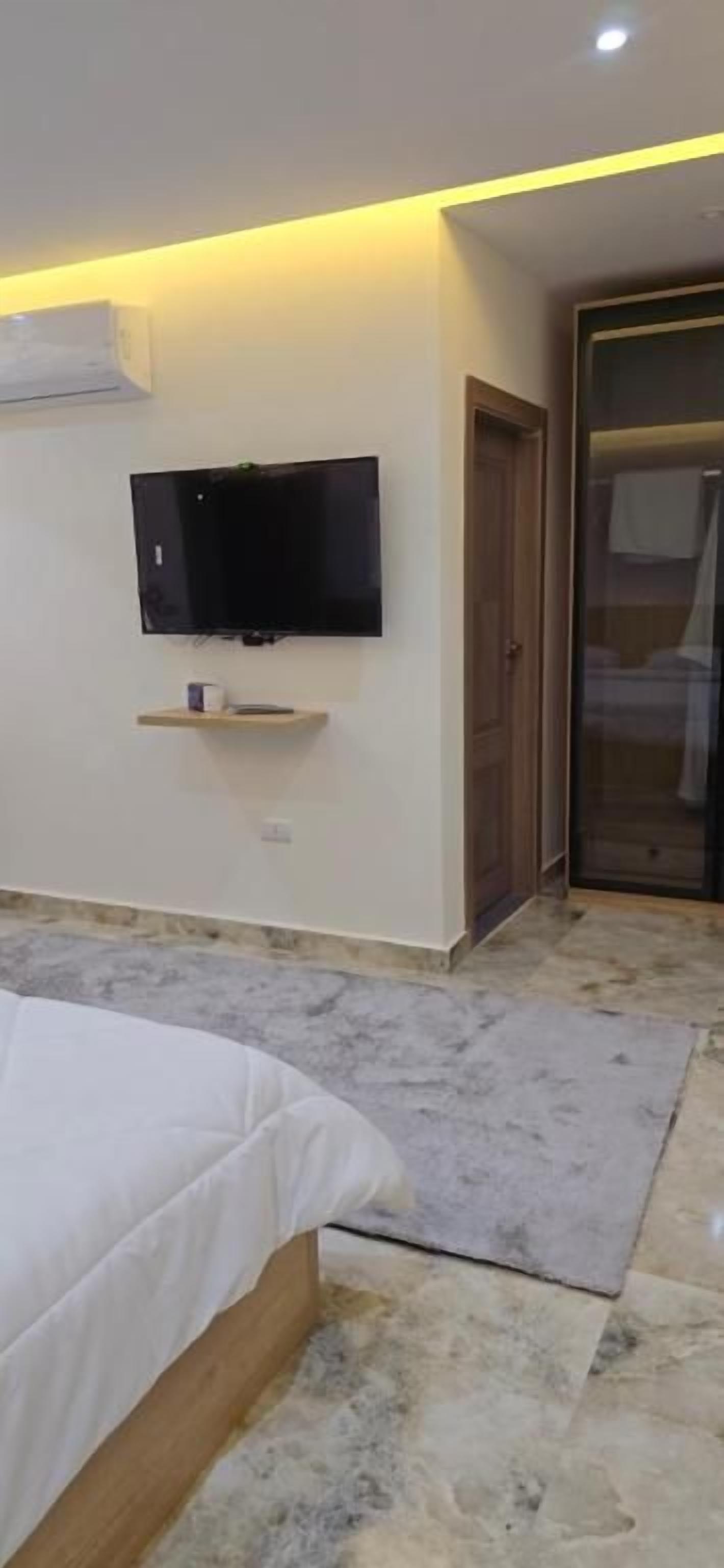 Un dormitorio con una cama, un televisor montado en la pared y una puerta corredera.