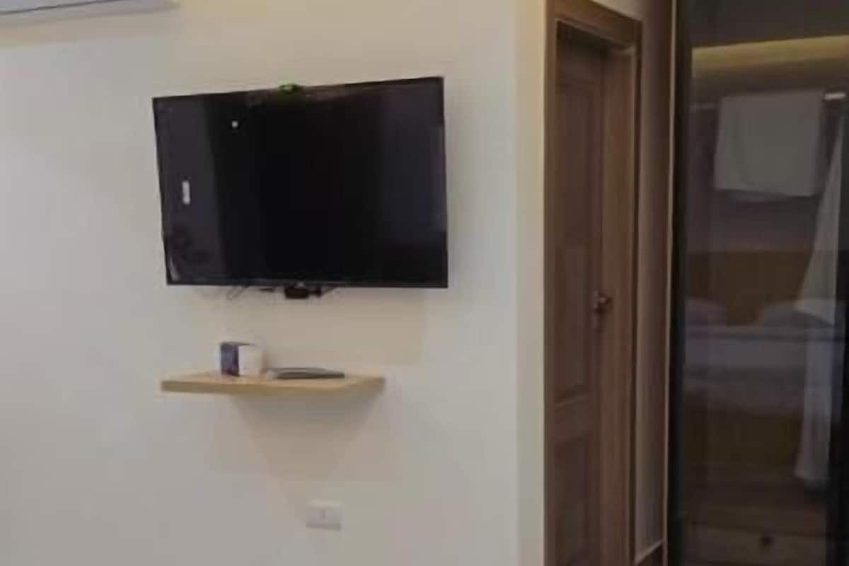 A bedroom with a bed, a television mounted on the wall, and a sliding door.