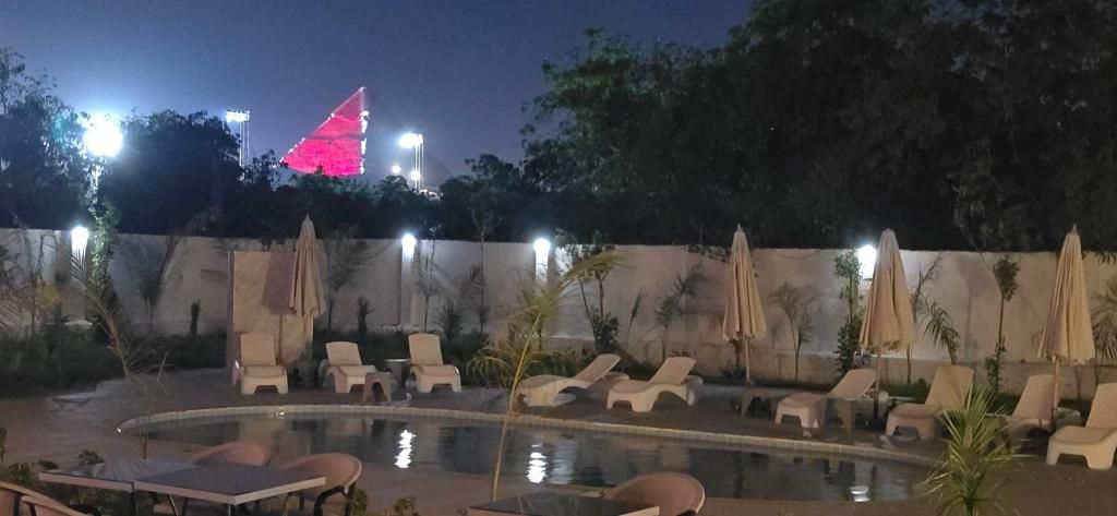 A poolside area with lounge chairs and umbrellas, surrounded by a low wall and trees.