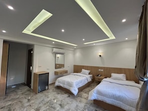 A hotel room with two beds, a desk, a mirror, and recessed ceiling lighting. - Nakhil Pyramids Resort (Giza)