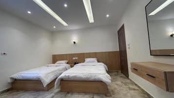 A bedroom with two single beds, a wooden headboard, a marble floor, a wooden dresser, and a wall-mounted mirror.