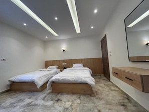 A bedroom with two single beds, a wooden headboard, a marble floor, a wooden dresser, and a wall-mounted mirror. - Nakhil Pyramids Resort (Giza)