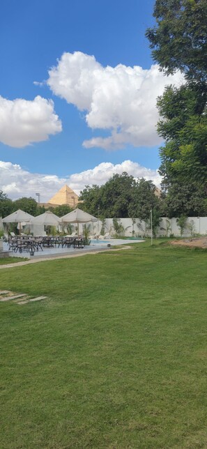Zona verde con asientos al aire libre y una piscina.