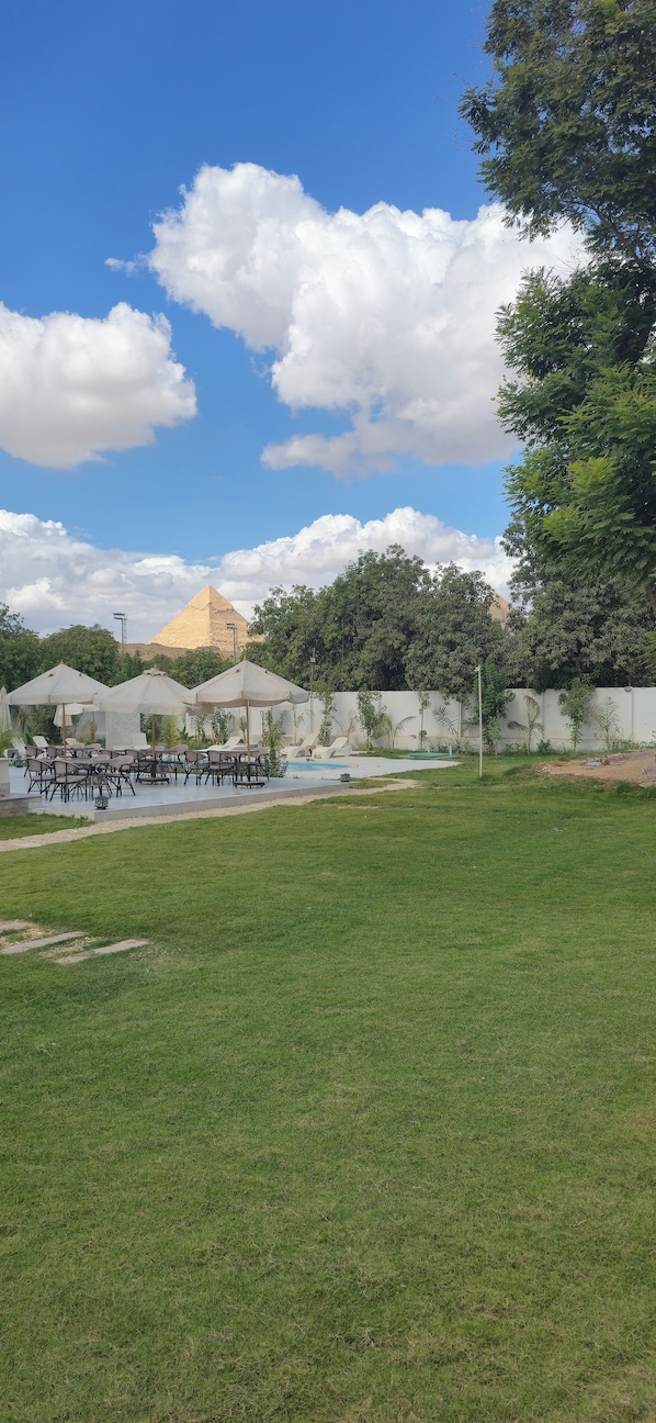 A grassy area with outdoor seating and a pool. - Nakhil Pyramids Resort (Giza)