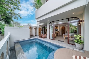 A modern outdoor pool area with a glass-enclosed patio, seating, and a view of the interior. - 3BR Private Pool Villa with Rooftop in Pererenan Near Canggu (Pererenan)