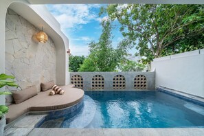 A swimming pool with a stone wall, a seating area with cushions, and a hanging light fixture. - 3BR Private Pool Villa with Rooftop in Pererenan Near Canggu (Pererenan)