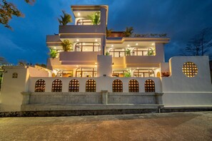 A multi-story building with balconies, a gated entrance, and a well-lit facade. - 3BR Private Pool Villa with Rooftop in Pererenan Near Canggu (Pererenan)
