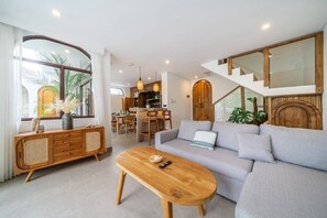 A modern living room with a sofa, wooden coffee table, and a dining area with chairs. - 3BR Private Pool Villa with Rooftop in Pererenan Near Canggu (Pererenan)