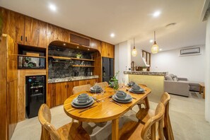 A modern kitchen with wooden cabinets, a built-in microwave, and a dining area with a wooden table set for four. - 3BR Private Pool Villa with Rooftop in Pererenan Near Canggu (Pererenan)
