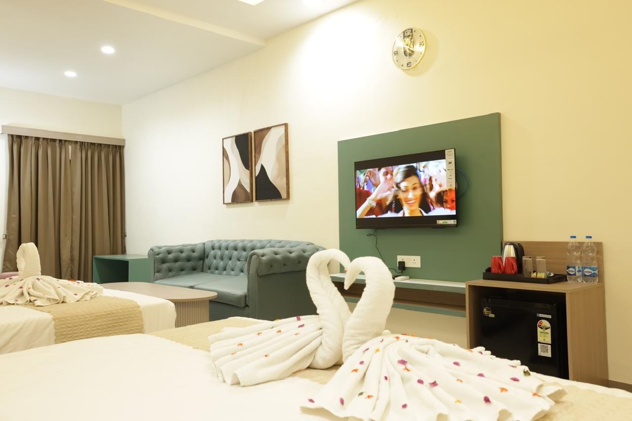 Ein Hotelzimmer mit zwei Betten, einer Sitzecke, einem Fernseher und einer Minibar.