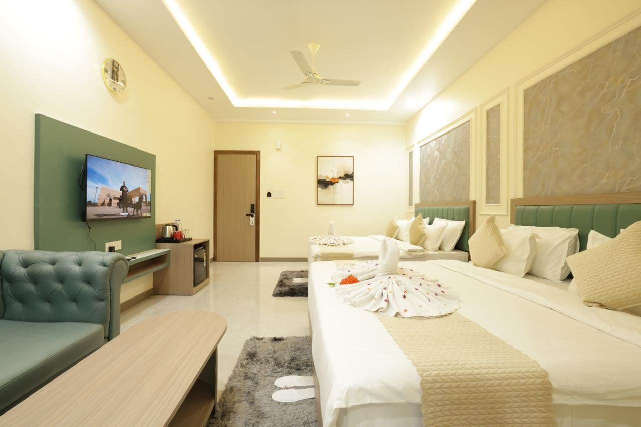 Una habitación de hotel con cama, sofá, televisión, ventilador de techo y un cuadro en la pared.