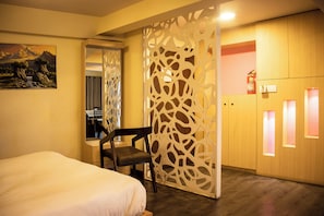 A hotel room with a bed, a chair, a decorative partition, and a wardrobe with a fire extinguisher. - One-bedroom studio in serene Lalitpur with AC (Lalitpur)