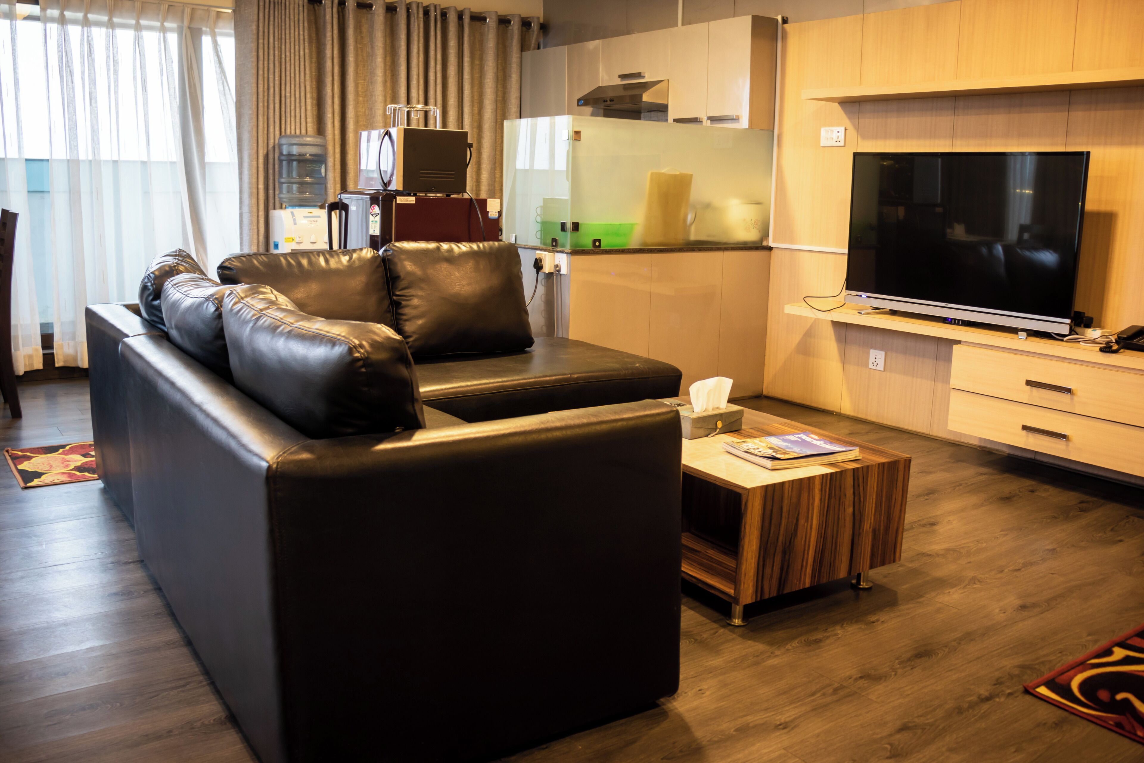 Una sala de estar moderna con un sofá de cuero, un televisor de pantalla plana y una mesa de centro de madera.