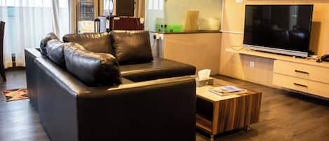 Una sala de estar moderna con un sofá de cuero, un televisor de pantalla plana y una mesa de centro de madera.