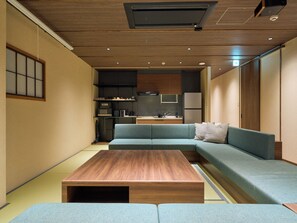 Un espacio habitable compacto con sofá, una mesita de centro, kitchenette y puerta corredera.