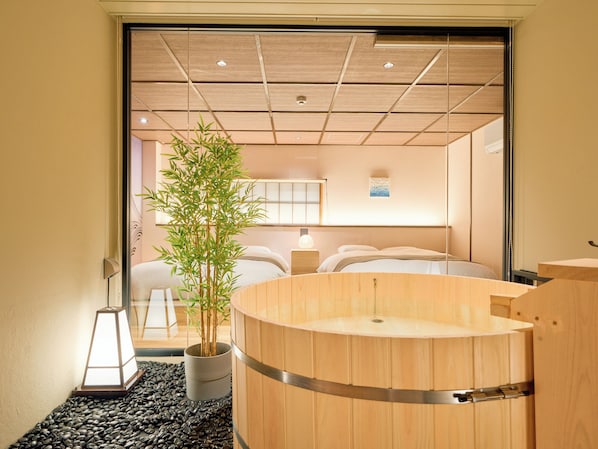 A traditional Japanese-style room with tatami flooring, a wooden soaking tub, a bamboo plant, and a sliding shoji screen.