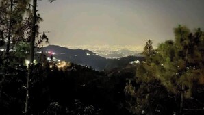 A nighttime view of a mountainous area with a city in the distance. - Rudrashray Paradise Mussoorie (Mussoorie)