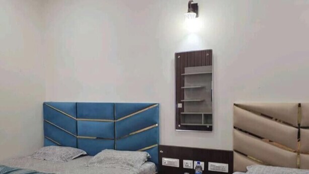 A hotel room with two beds, a bedside table with a water bottle, and a wall-mounted shelf. - Rudrashray Paradise Mussoorie (Mussoorie)