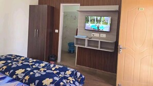 A bedroom with a bed, a wardrobe, a television mounted on the wall, and a door with a number. - Rudrashray Paradise Mussoorie (Mussoorie)