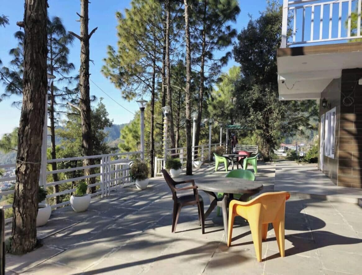 Un patio al aire libre con una mesa y sillas, rodeado de árboles y vistas al paisaje.