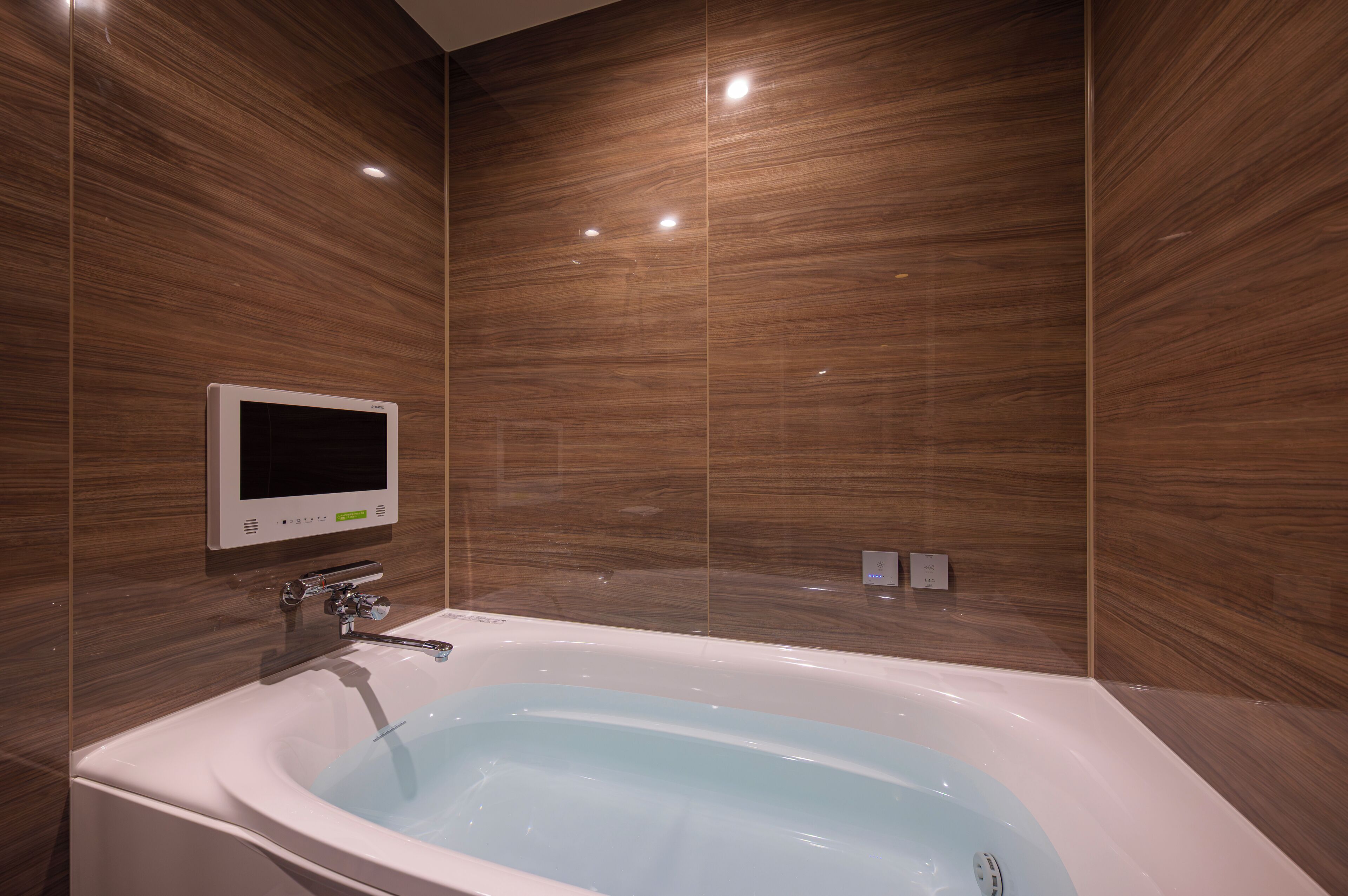 A modern bathroom with a freestanding bathtub, a wall-mounted control panel, and a built-in showerhead.