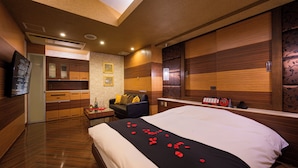 Una habitación de hotel con cama, escritorio, silla, espejo y televisor.