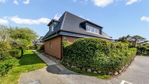 Ein zweistöckiges Haus mit Backsteinfassade, Ziegeldach und einem gepflegten Garten.