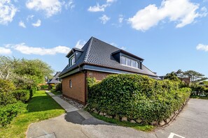 A two-story house with a brick facade, a tiled roof, and a well-maintained garden. - Modern 3-room vacation apartment with approximately 75 m² of living space, accommodating up to 6 people (Wenningstedt-Braderup (Sylt))