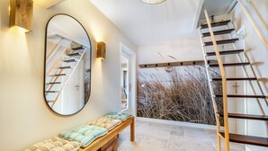 Ein modernes Interieur mit einer Bank, einer Treppe und einem großen Spiegel, der die Treppe reflektiert.