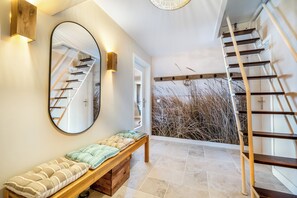 A modern interior with a bench, a staircase, and a large mirror reflecting the staircase. - Modern 3-room vacation apartment with approximately 75 m² of living space, accommodating up to 6 people (Wenningstedt-Braderup (Sylt))
