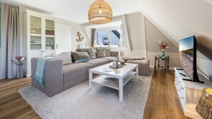 Ein modernes Wohnzimmer mit einer Couch, einem Couchtisch und einem Fernseher.