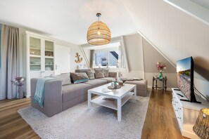 A modern living room with a sofa, coffee table, and a television. - Modern 3-room vacation apartment with approximately 75 m² of living space, accommodating up to 6 people (Wenningstedt-Braderup (Sylt))