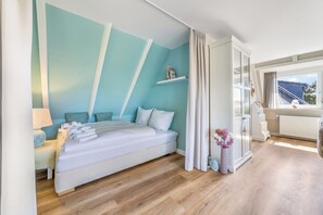 Un dormitorio con cama, mesita de noche, lámpara y vistas al exterior.