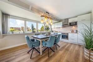Una cocina moderna con comedor, ventanas amplias y vistas al exterior.