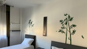 Een hotelkamer met twee bedden, een nachtkastje, een kunstwerk aan de muur en een raam met gordijnen.