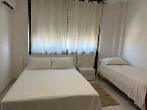 A bedroom with a large bed, a smaller bed, a nightstand, and a chair. - Two-Bedroom Family Apartment (Venezia)